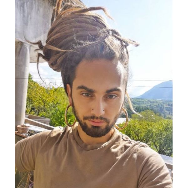 a man with Dreads Voluminous Man Bun Hairstyle with huge earrings
