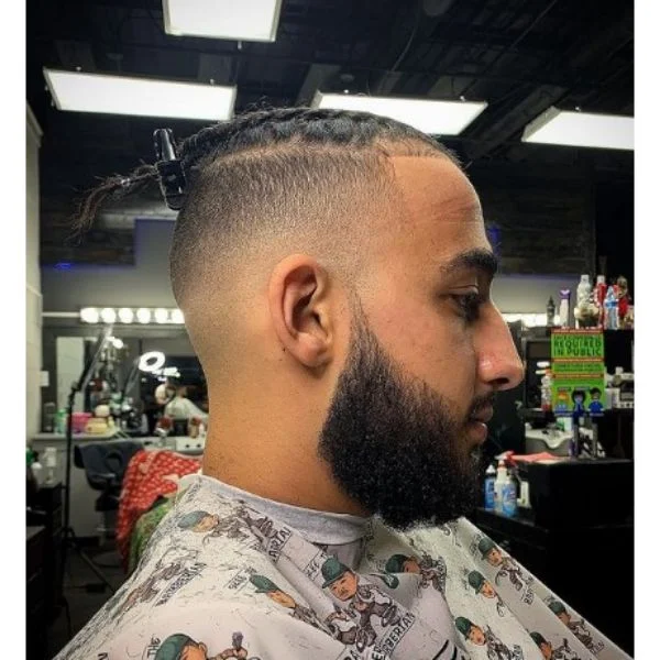 um homem com Box Braids e barba em uma barbearia