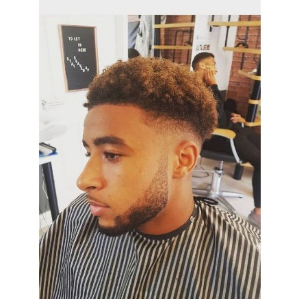  Low Fade With Curly Top And Subtle Brown Highlights