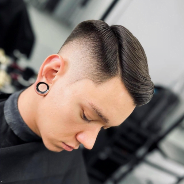 Young man wearing earrings with his Mid Fade Side Part Hairstyle