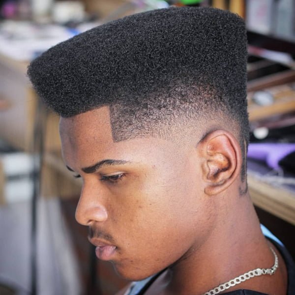 Black young guy wearing necklace had his hair styled into Afro with Mid Bald Fade