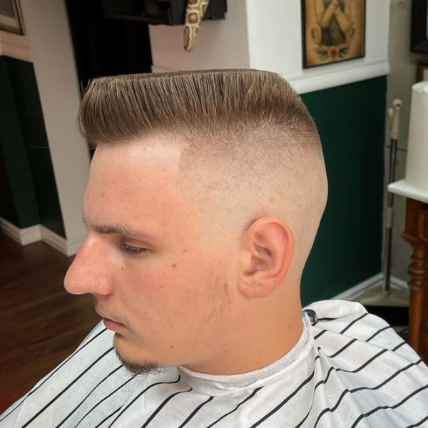 Guy wearing black and white barber's cape with Midget Trim Flat Top