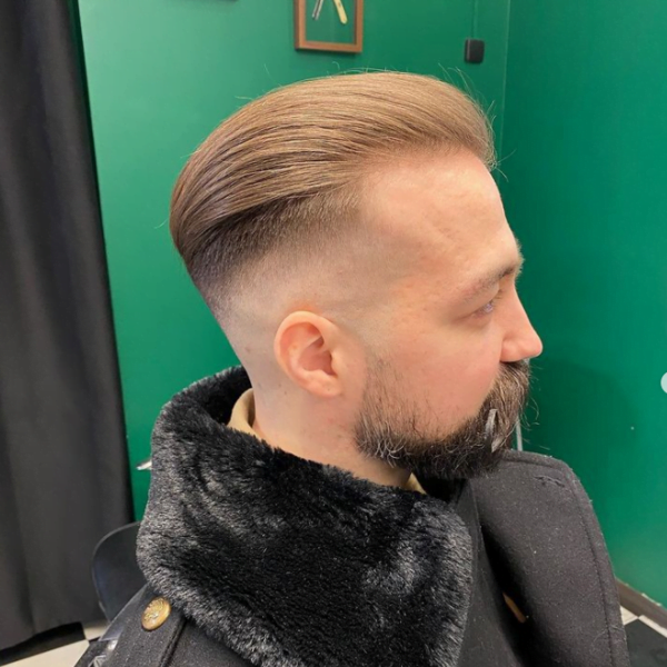 Man wearing coat had his hair styled into Slicked Back with High Temple Fade